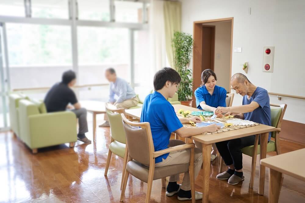 デイサービス施設で介護士が高齢者と一緒にリハビリ活動をしている様子