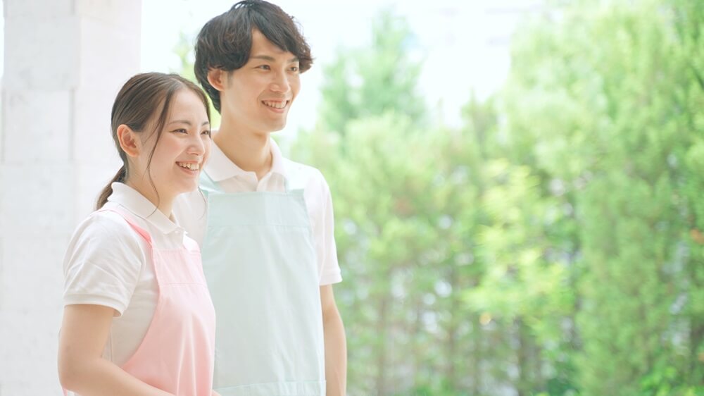 笑顔の男女の介護士が屋外で並んで立っている様子