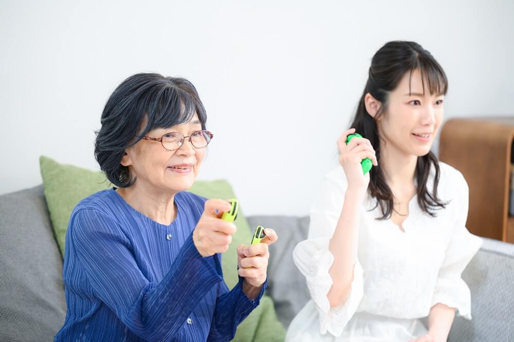 若い女性とテレビゲームをする高齢者